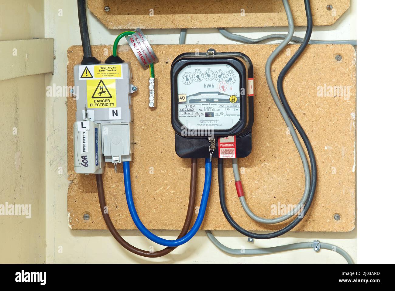 Domestic consumer electrical supply connected to PME system and analogue electric meter indicating how much electric / energy has been consumed. Stock Photo