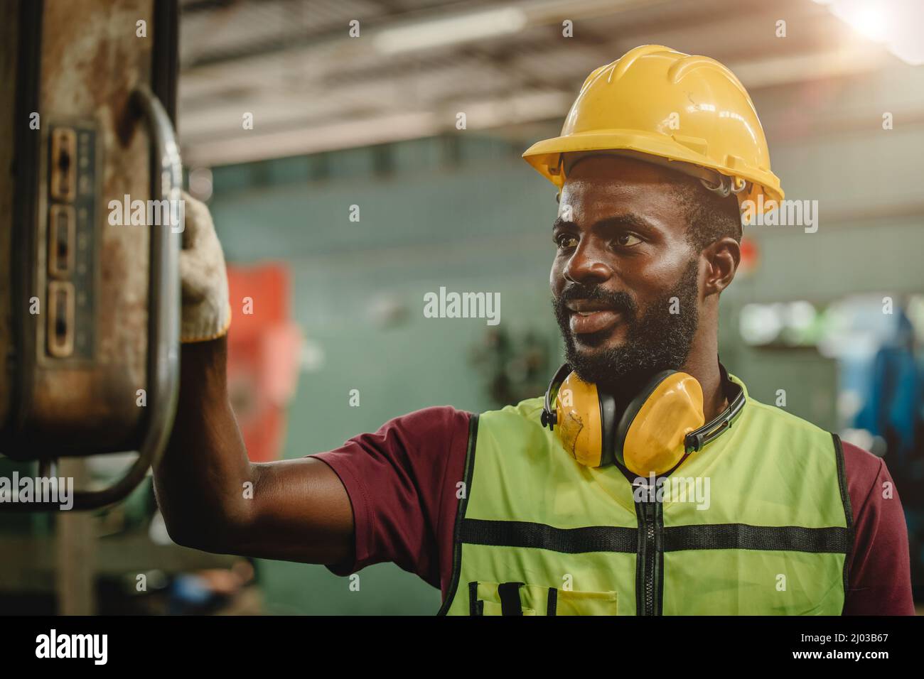 Black African professional worker working in heavy industry factory wearing engineer suit and helmet for safety.worker operating machine. Stock Photo