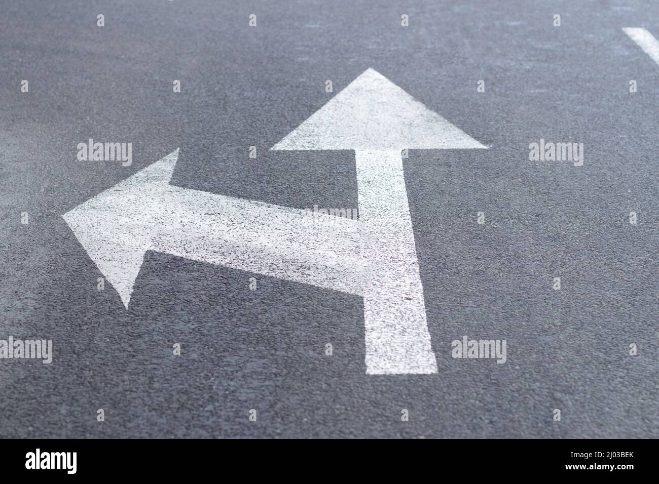 Arrows of road markings on an asphalt road for the direction of movement straight or to the left Stock Photo
