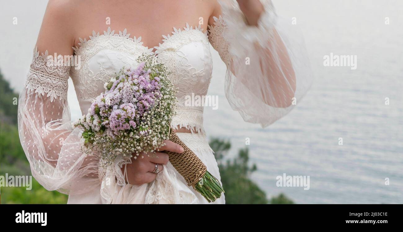 bride flower, closeup hand of bride holding flower bouquet outdoor. body part of a woman wearing vintage wedding dress with selective focus. Stock Photo