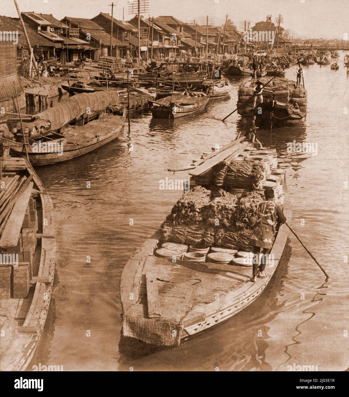Canal in Tokyo with boats laden with food and moored alongside being poled along, Japan, about 1900 Stock Photo