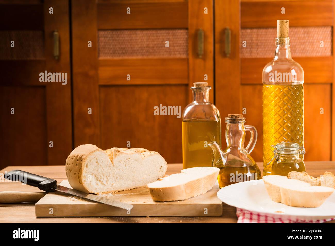 Still life with bread and several bottles and containers with extra virgin olive oil on a rustic wooden table. Stock Photo