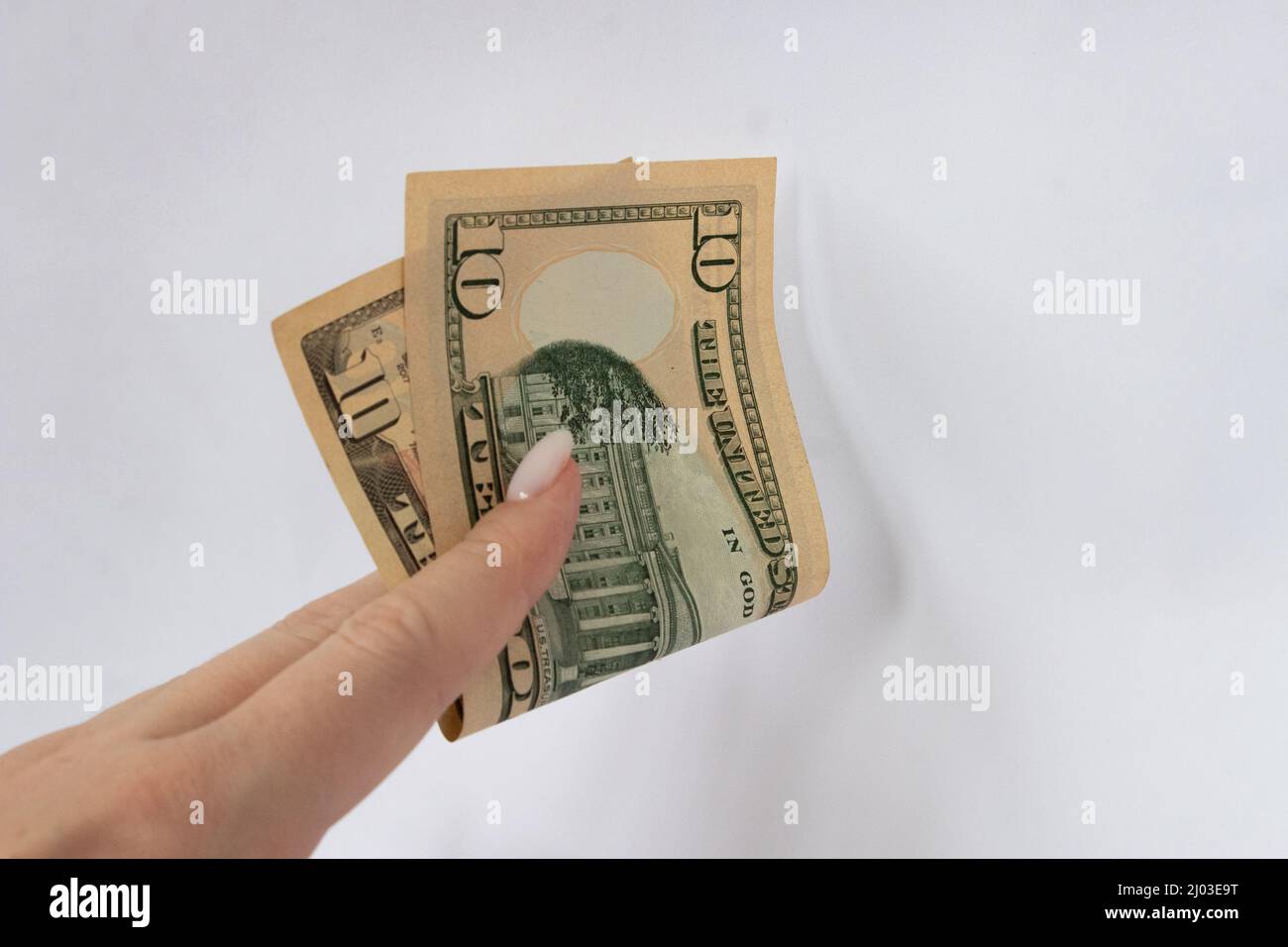 10 dollars in the hand close-up on a white isolated background. A ten-dollar bill Stock Photo