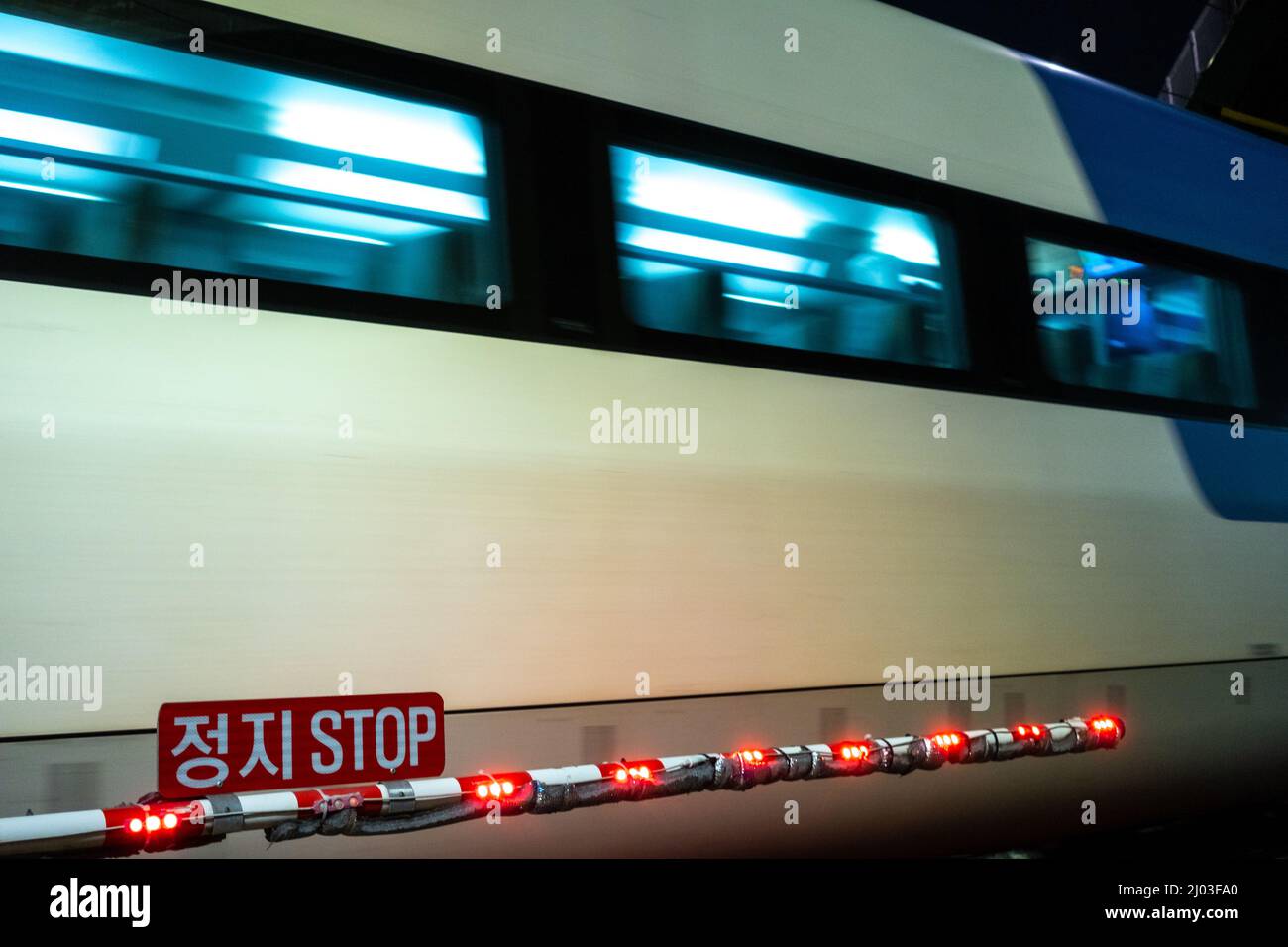 Moving train near an illuminated stop strip at a station Stock Photo ...