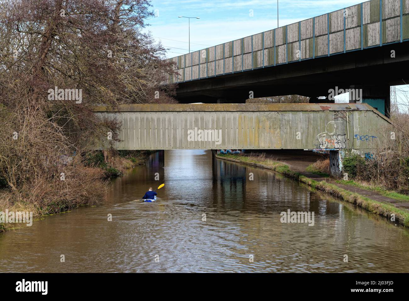 A lone kayaker passing under the M25 elevated motorway bridge that
