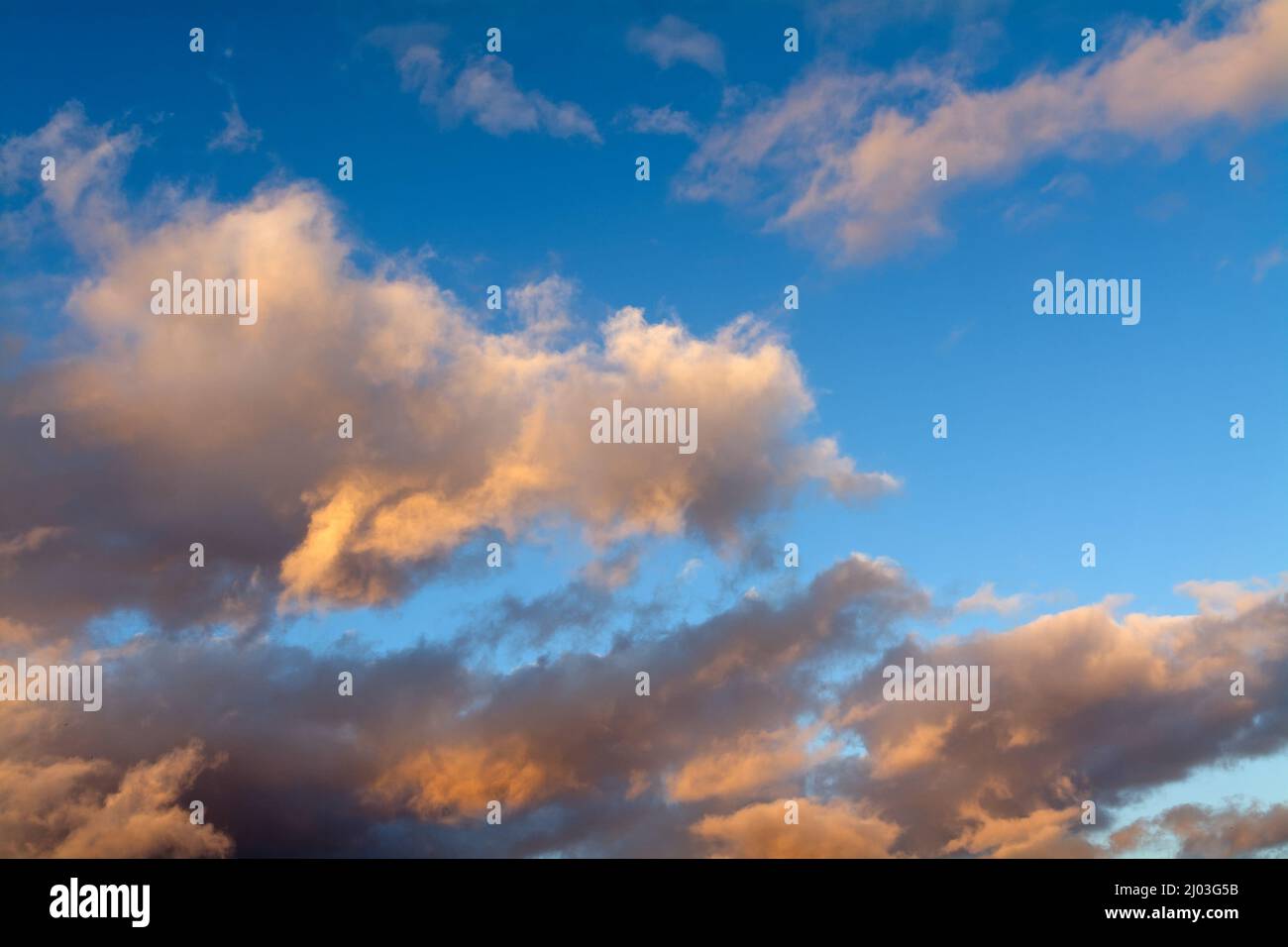 Colourful soft wispy orange clouds against a blue winters sky Stock Photo