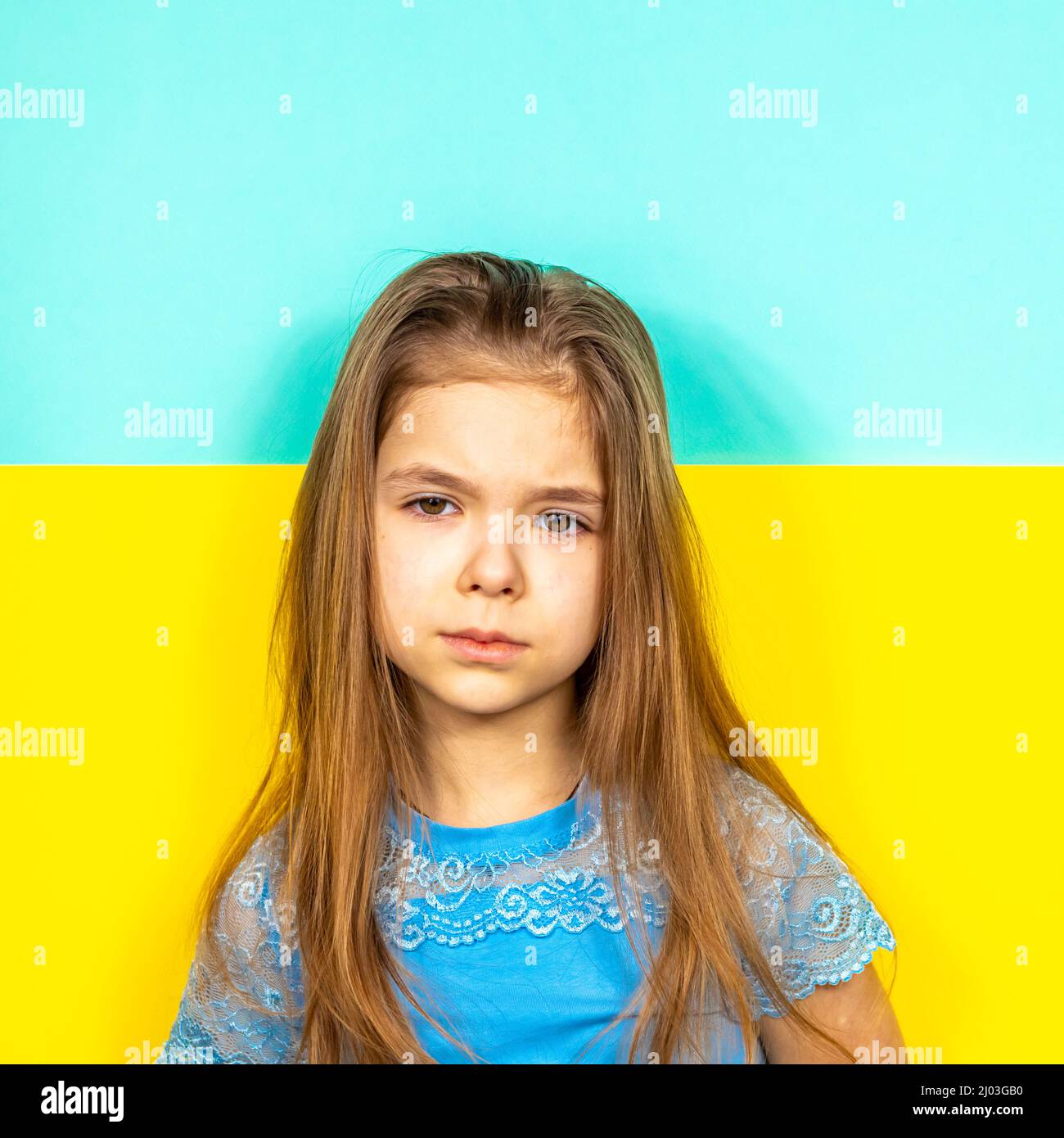 Sad girl on the background of the Ukrainian flag. Stop the war in Ukraine. The concept of peace in Ukraine. Children against war. Place for text. Stock Photo