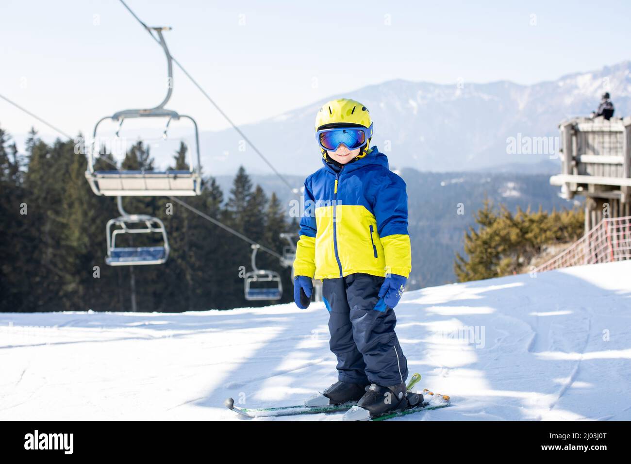 Cute toddler child in colorful ski wear, skiing in Italy on a sunny day, kids and adults skiing together. Family vacation Stock Photo