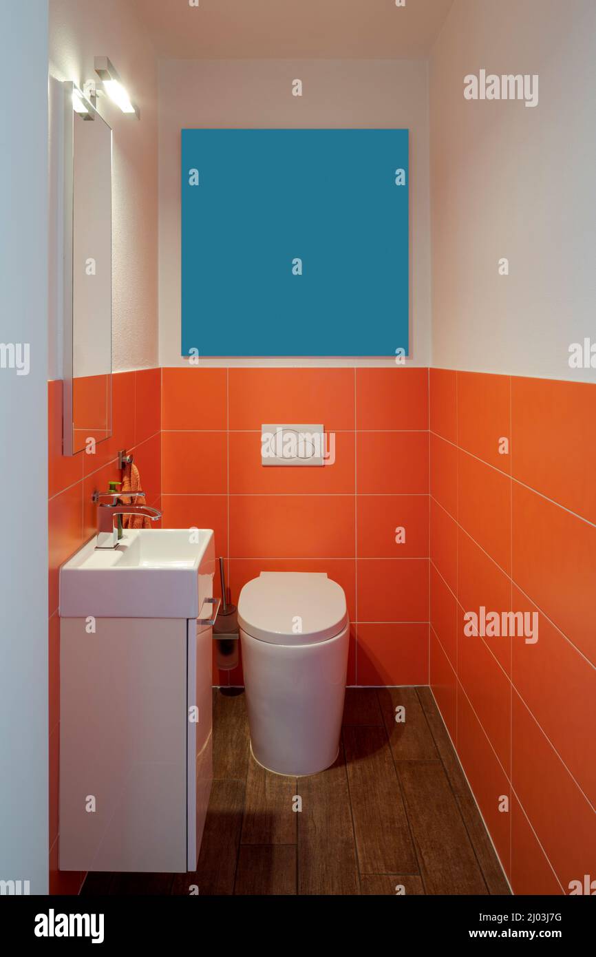 Very small bathroom front view with sink, mirror and toilet. Very colorful, no one inside Stock Photo