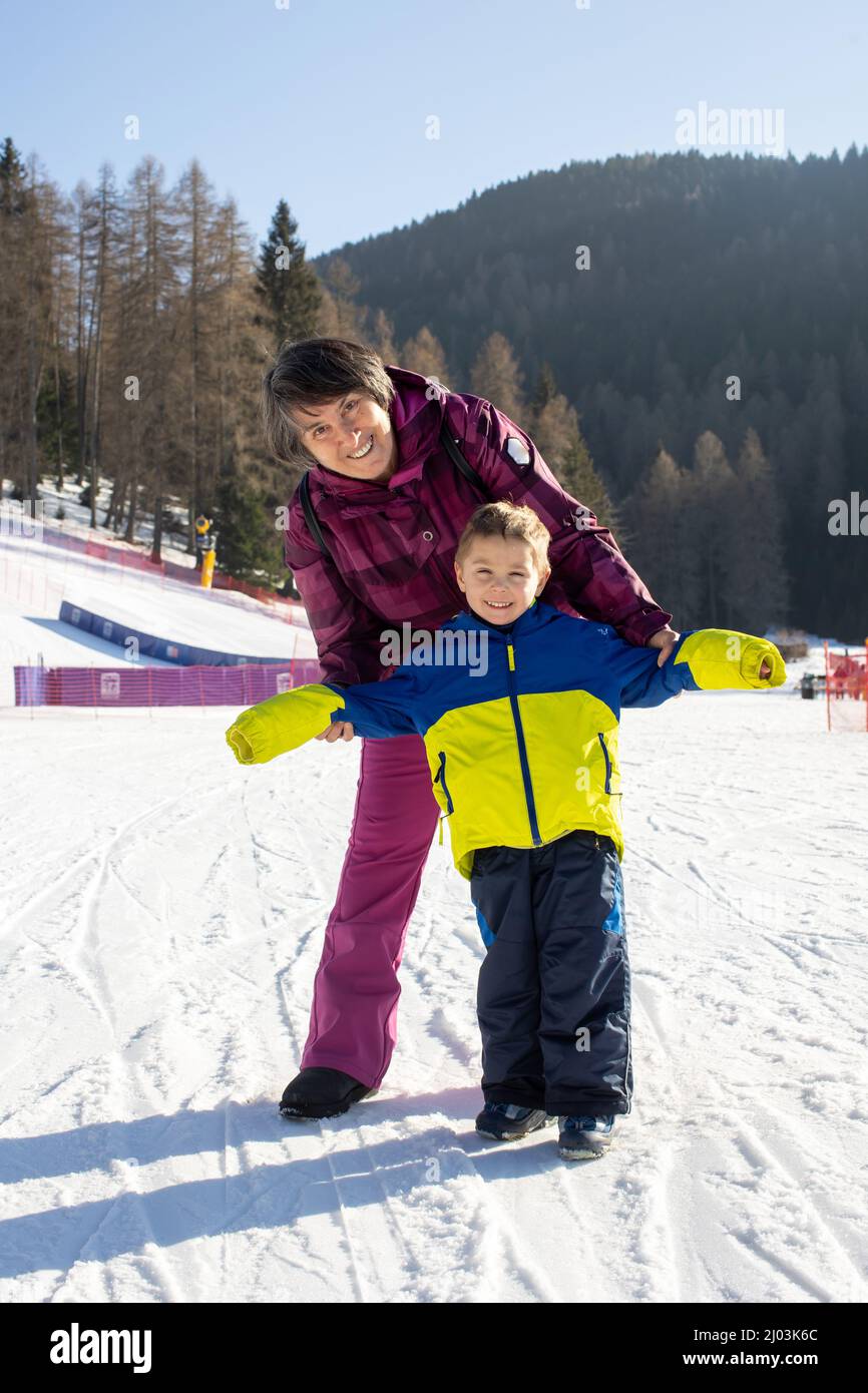 Happy family, grandmother and baby boy on a ski slope in Italy on a sunny day, kids and adults skiing together Stock Photo