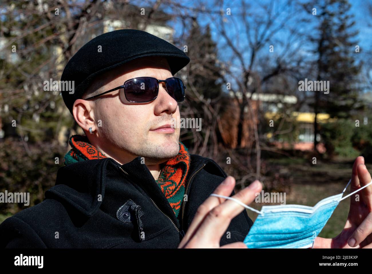 A young man taking off his protective face mask. Stock Photo