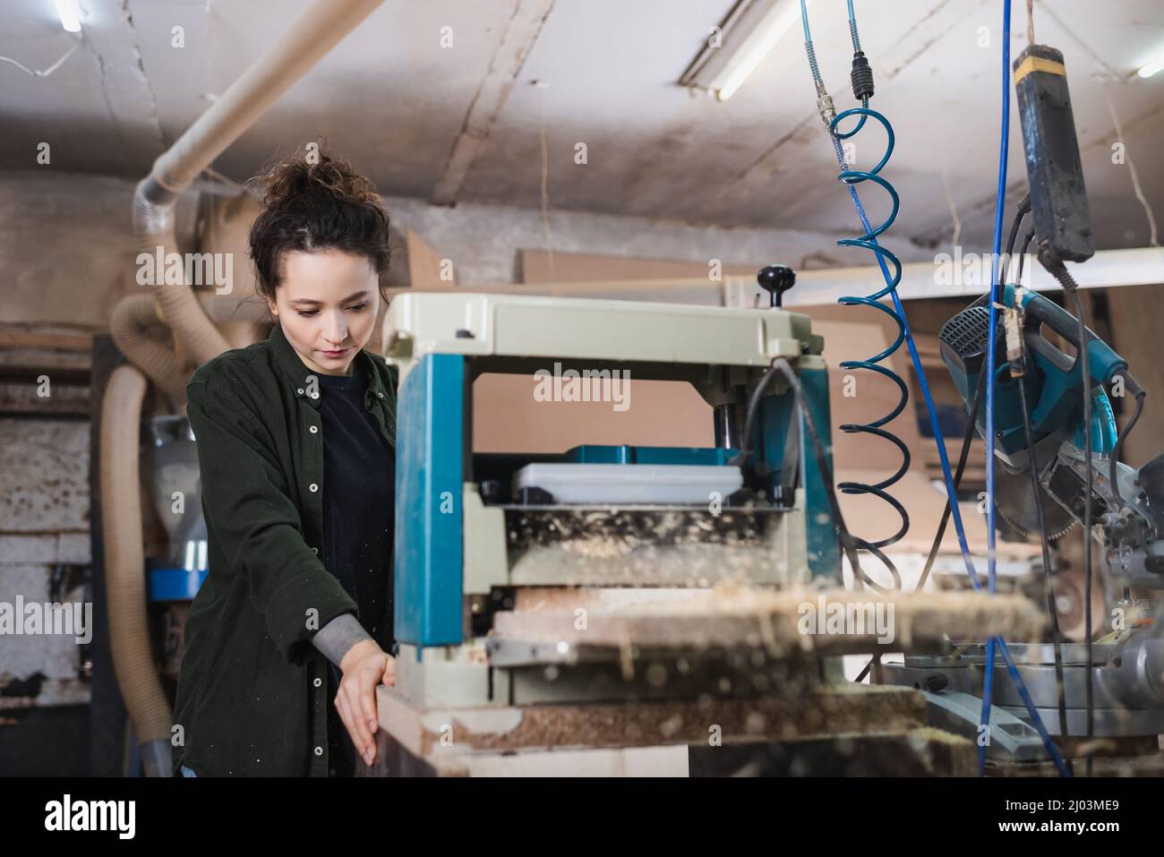 Woodworker using thickness planer while working in Stock Photo