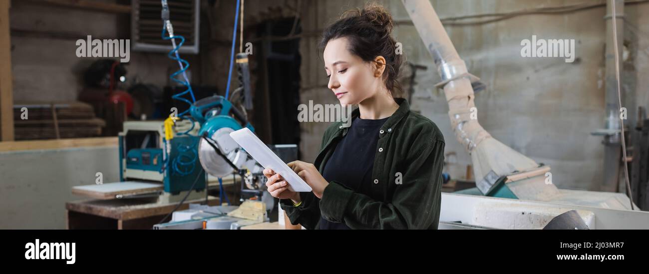 Young carpenter using digital tablet in workshop, banner Stock Photo