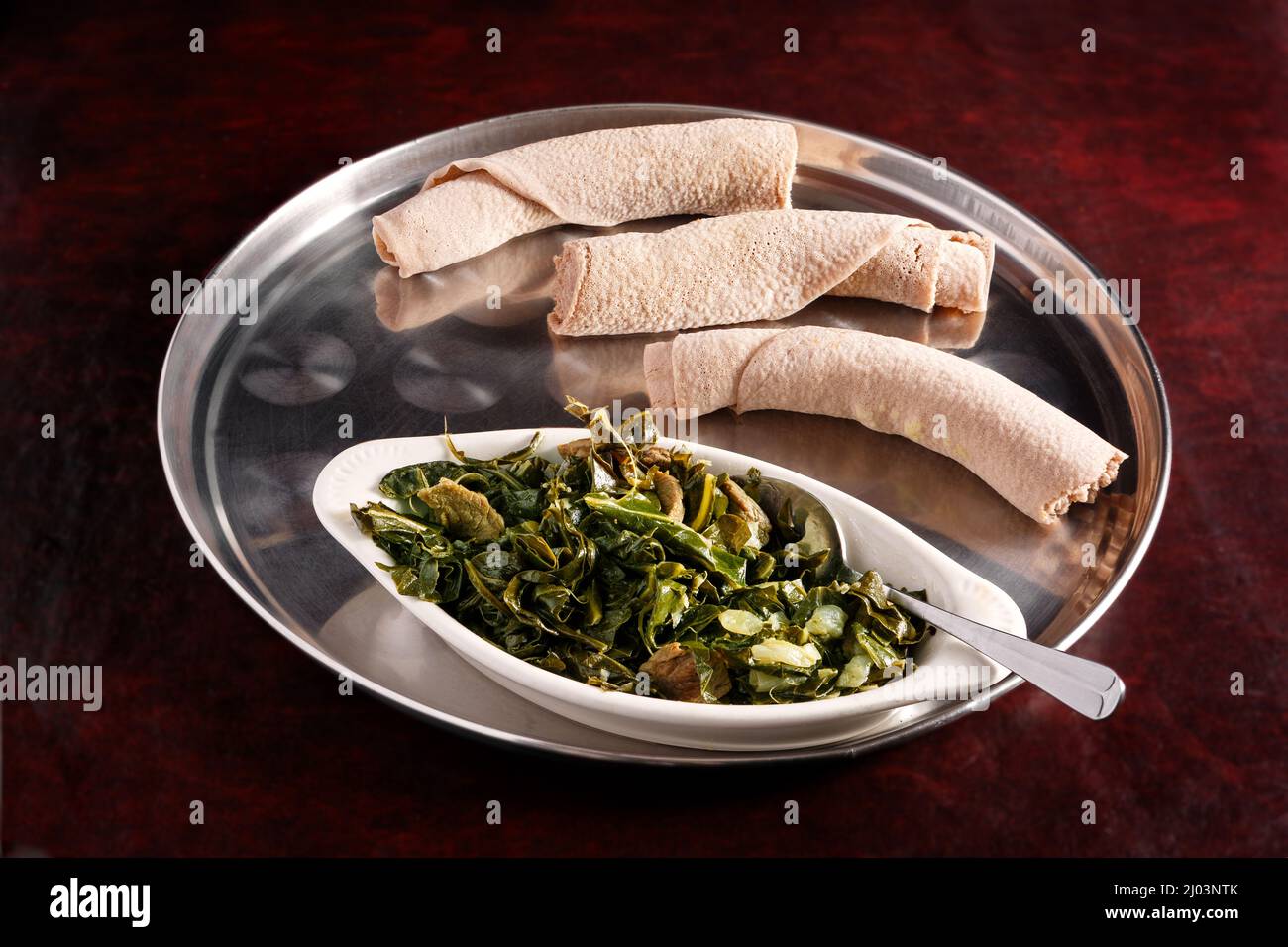 Ethiopian gomen besiga (stewed collard greens) with injera bread Stock