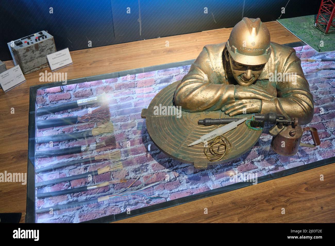 A bronze, metal sculpture of an underground telephone cable worker. At