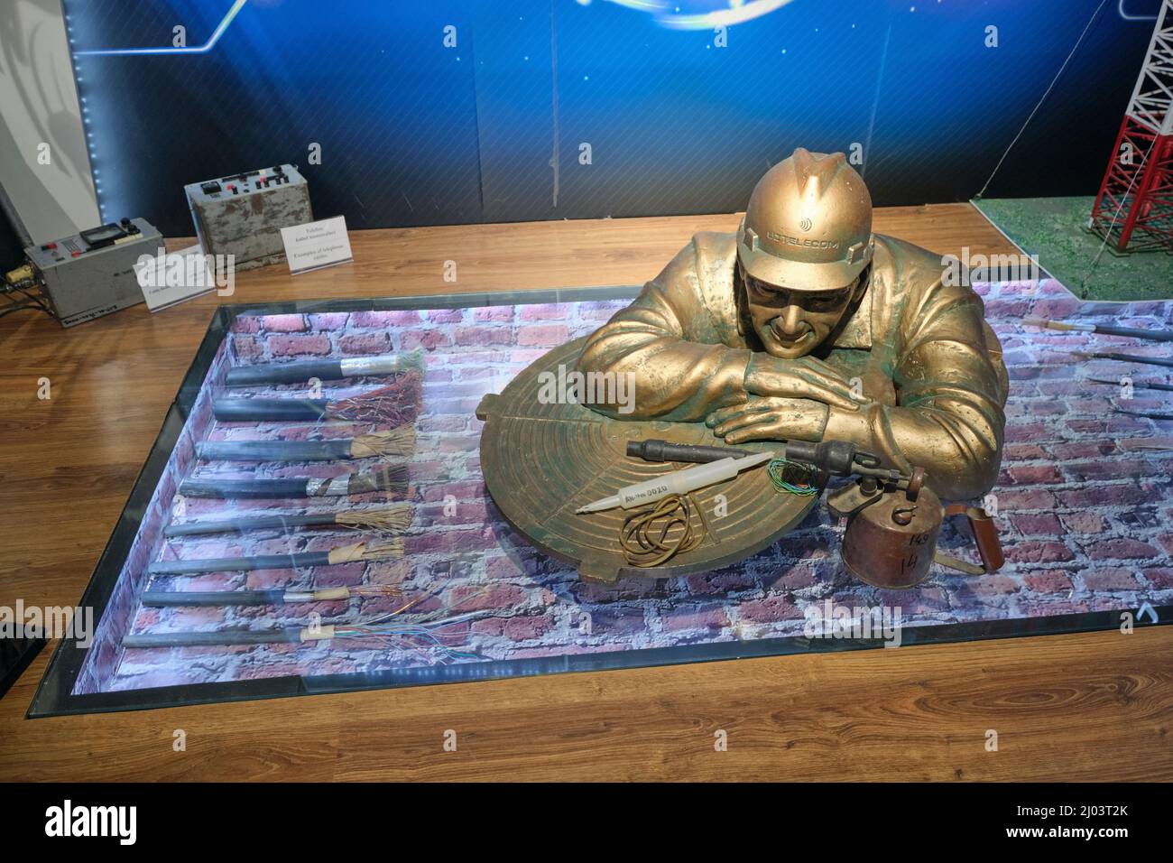 A bronze, metal sculpture of an underground telephone cable worker. At