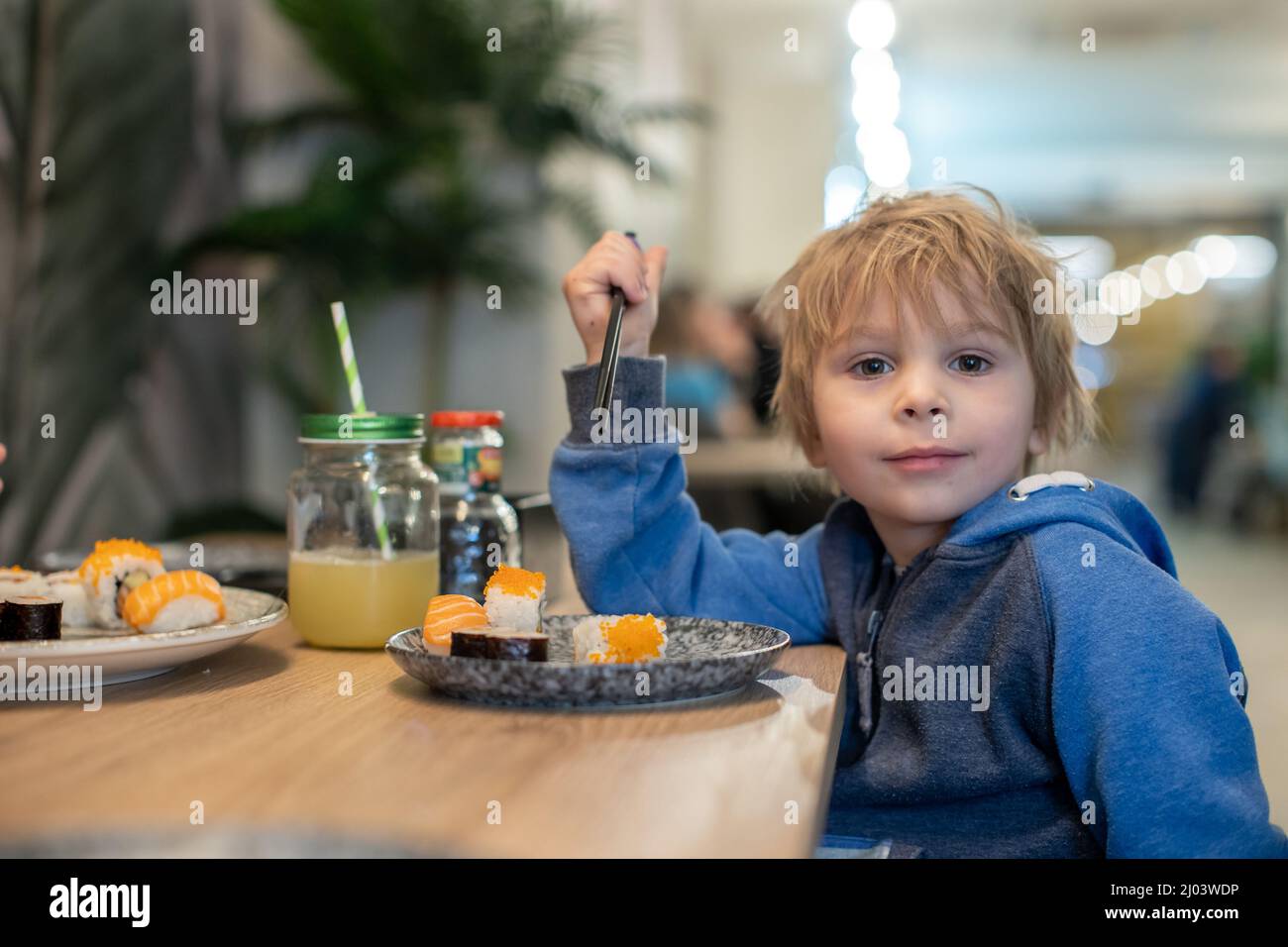 Child, eating japanese sushi and noodles with chopsticks in a restaurant, dinnertime Stock Photo