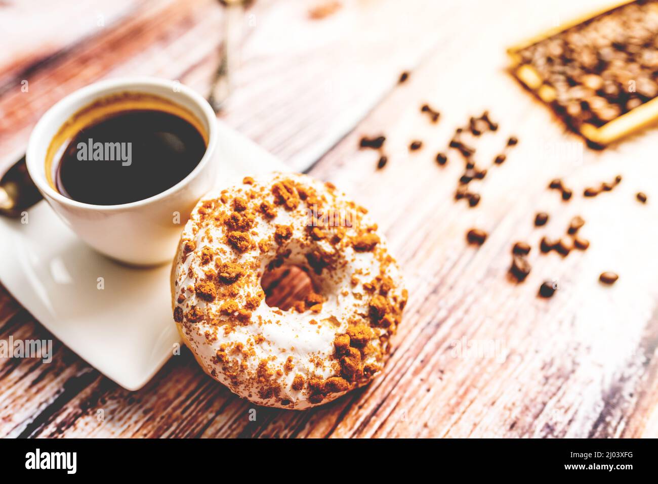 White donut with chocolate sprinkle and cup of coffee on wood table Stock Photo