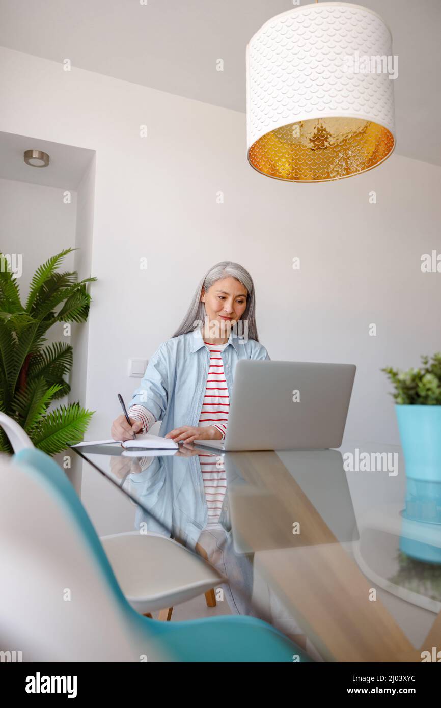 Woman using notebook and taking notes at home Stock Photo