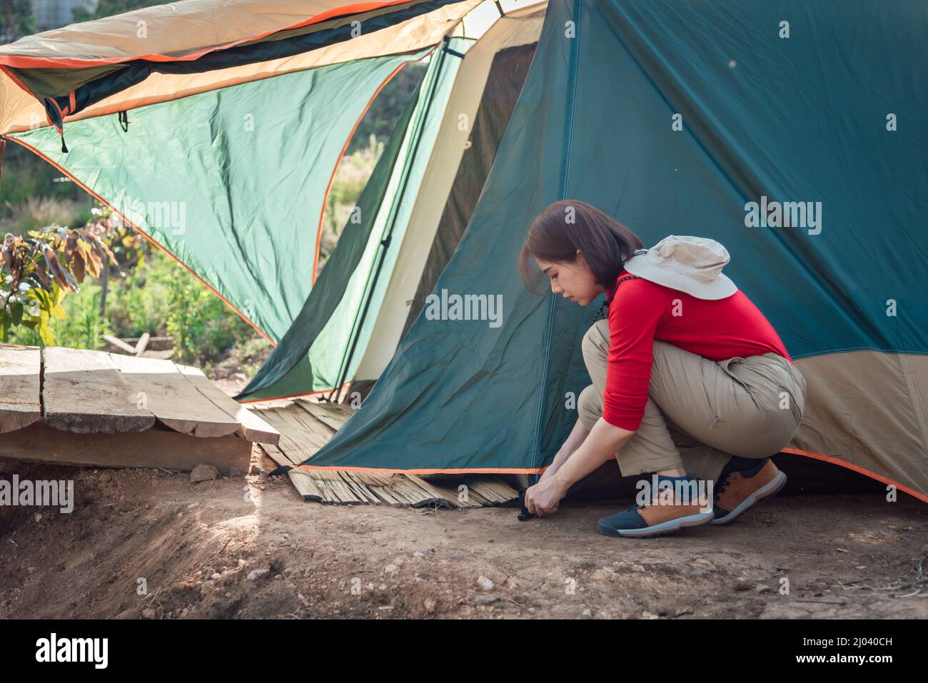 An Asian woman is pitching a tent at Hadubi viewpoint, Chiang Mai, Thailand. Stock Photo