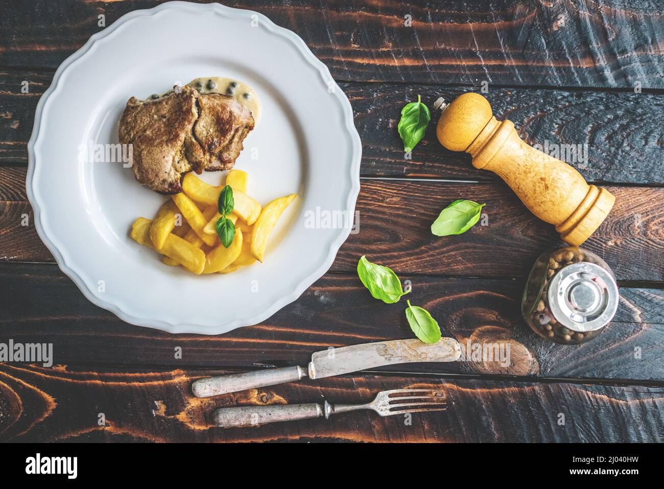 Grilled pork neck with pepper sauce and potato fries on wooden table Stock Photo
