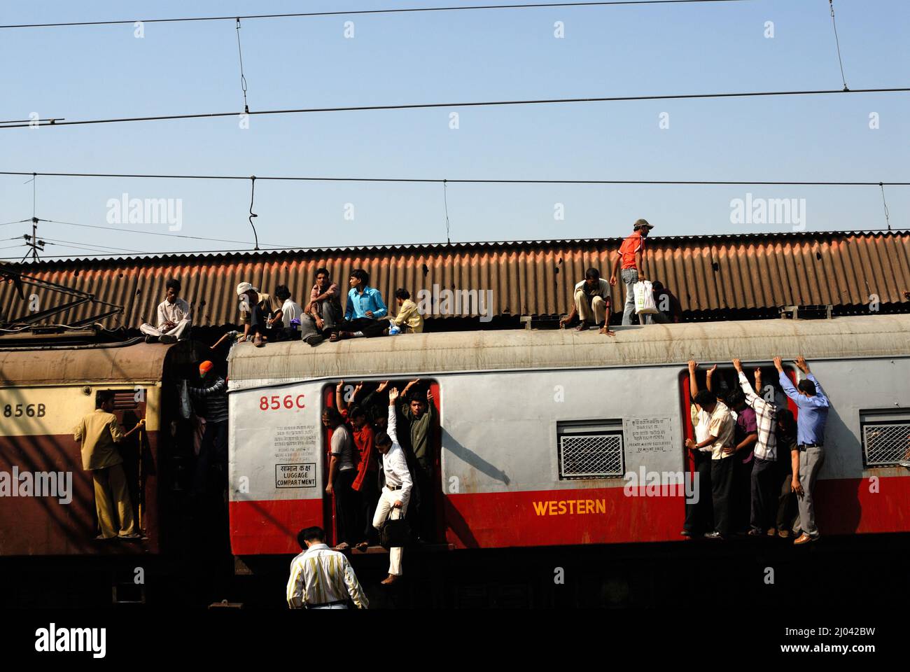 Indian commuters travel on the roof of a train performing stunts on local trains; 6 billion commuter travel in local trains of western suburb Mumbai. Stock Photo