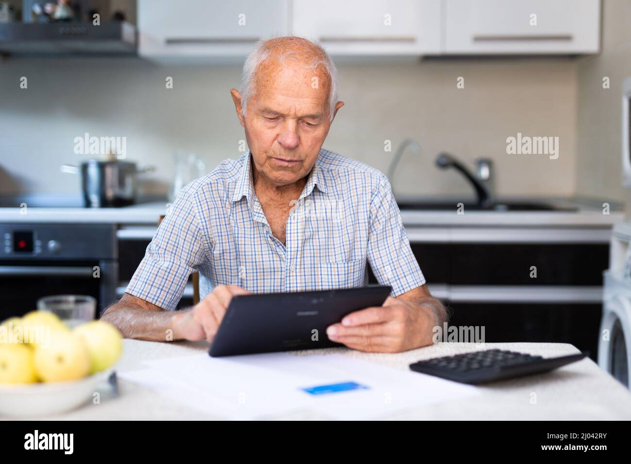 Senior man with tablet making purchases at home Stock Photo