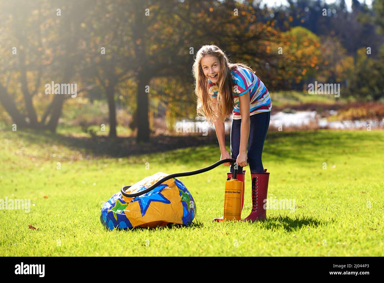 Schools out and summer is here. Portrait of a teenage girl inflating an inflatable ball outdoors. Stock Photo