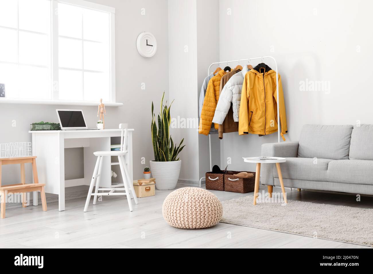 Interior of light room with modern workplace and warm jackets Stock Photo