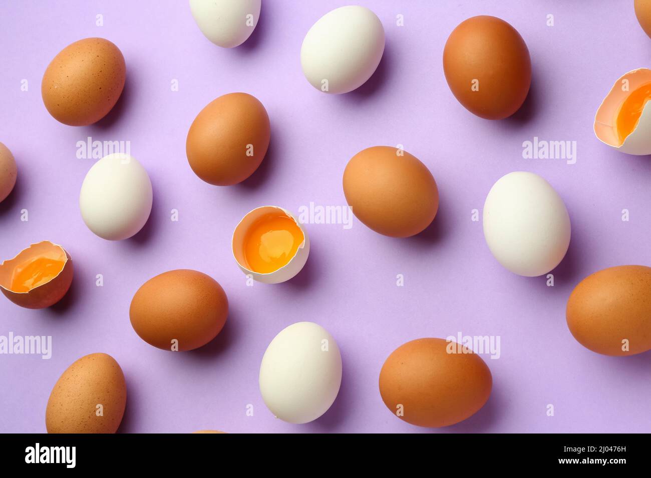 Cracked and whole chicken eggs on purple background Stock Photo - Alamy