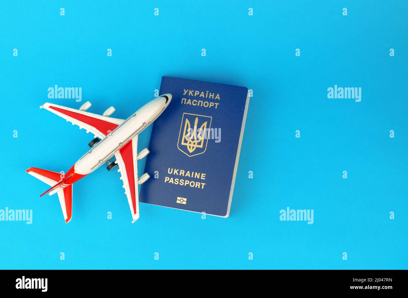 Passport of a citizen of Ukraine and a toy plane on a blue background. Inscription in Ukrainian Ukraine Passport. Stock Photo