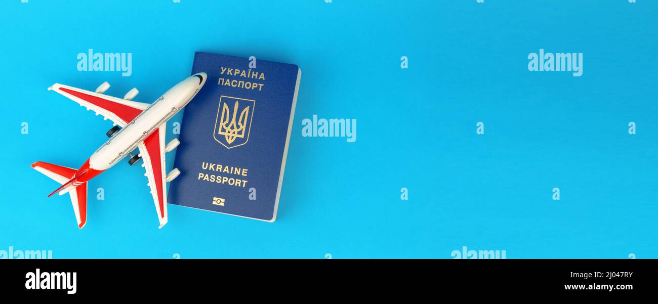 Passport of a citizen of Ukraine and a toy plane on a blue background, a banner. Inscription in Ukrainian Ukraine Passport. Stock Photo