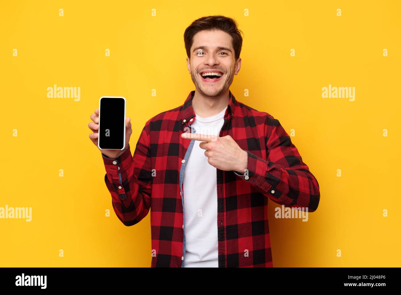 Cheerful guy pointing at empty smart phone screen Stock Photo