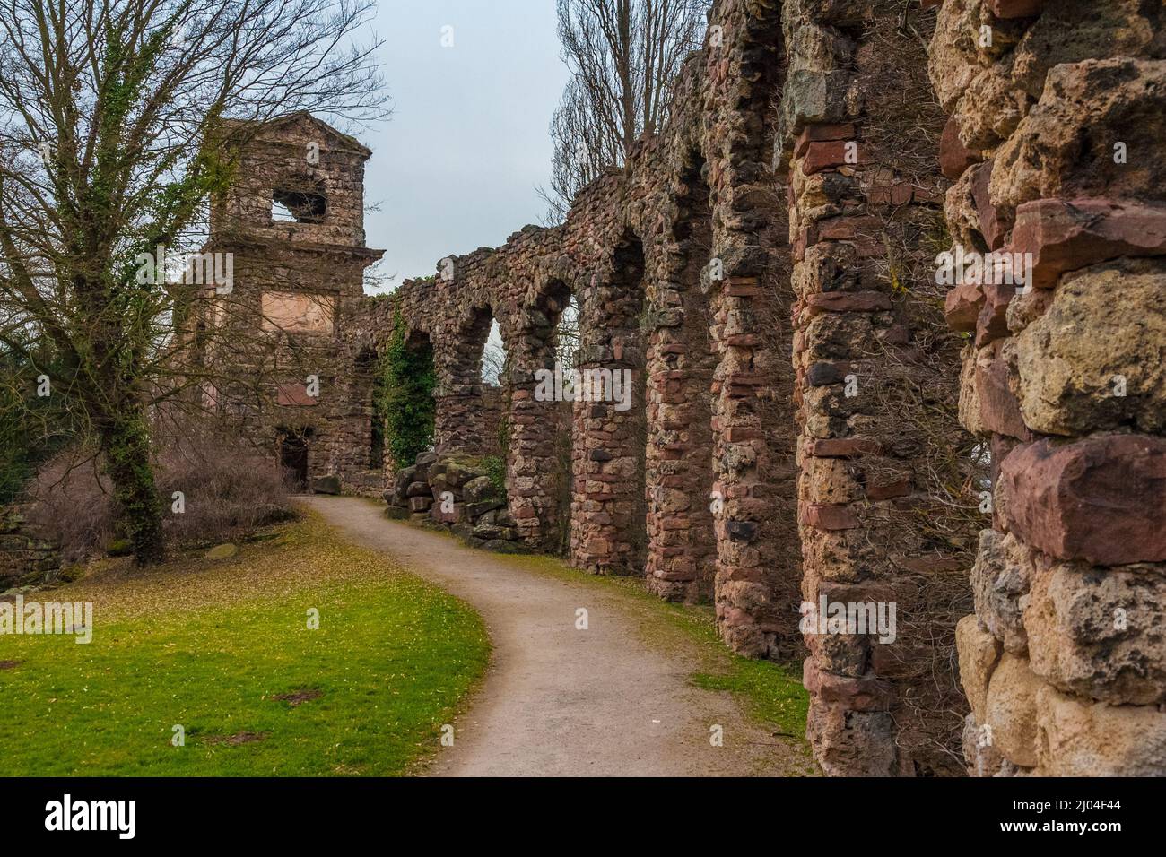 The walkway along the artificial ruins of the Roman aqueduct, leading to the likewise artificial ruins of a Roman water fort in the English landscape... Stock Photo