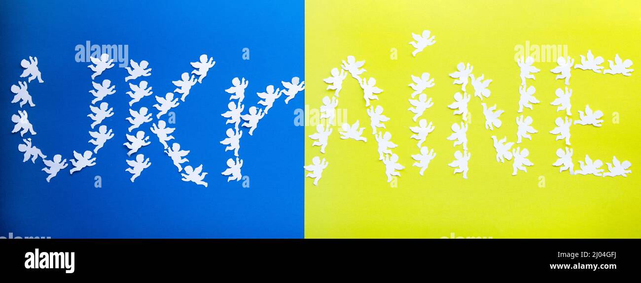 word Ukraine laid out from paper angels on a yellow - blue background, the colors of the national flag. Stand with Ukraine Stock Photo
