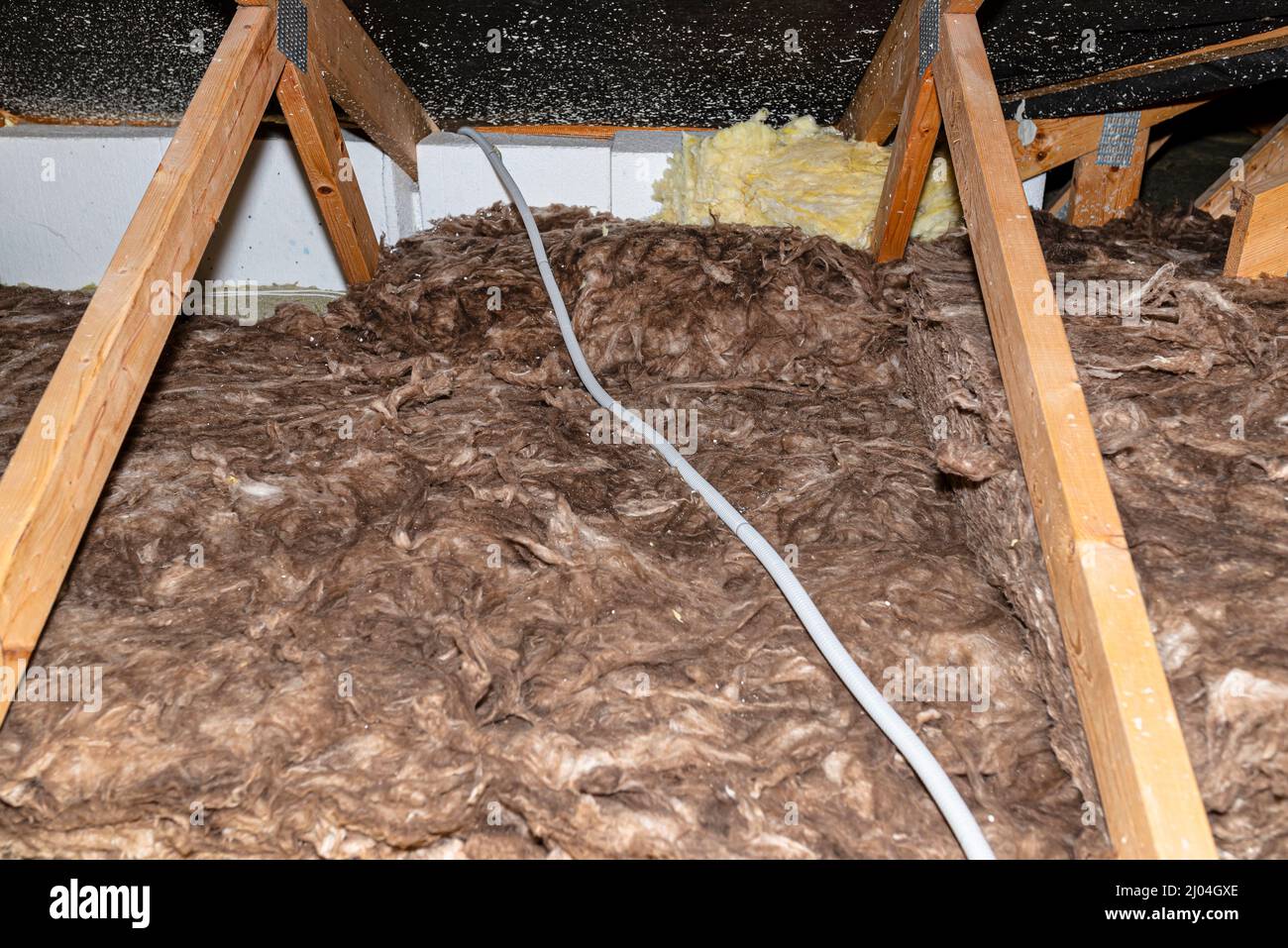Electric cable in a corrugated conduit on the roof trusses, located in the attic of the house