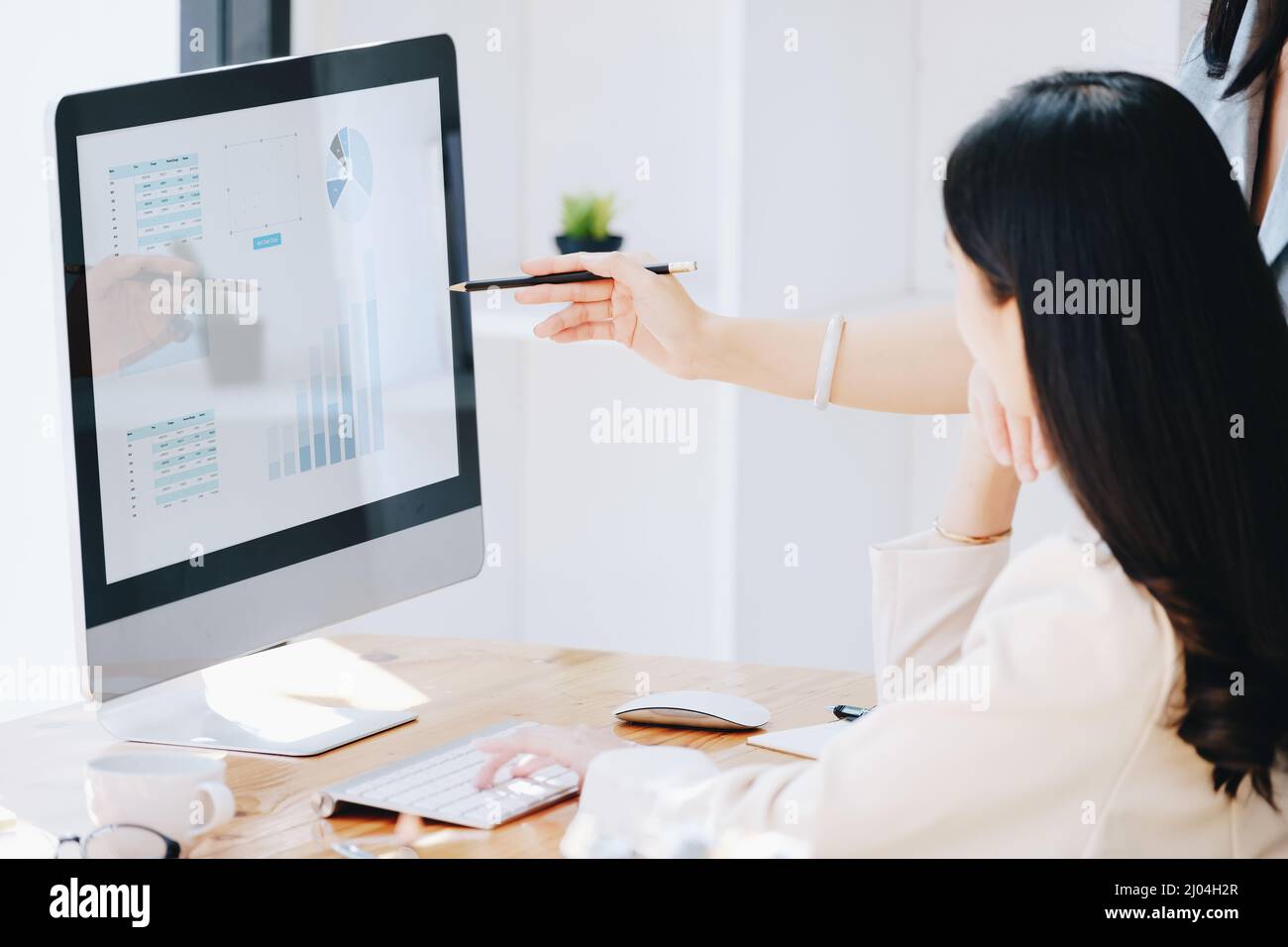 Consultation, Discussion, Marketing and Investment concept, female employee with pen is pointing at computer monitor to colleagues to draw conclusions Stock Photo