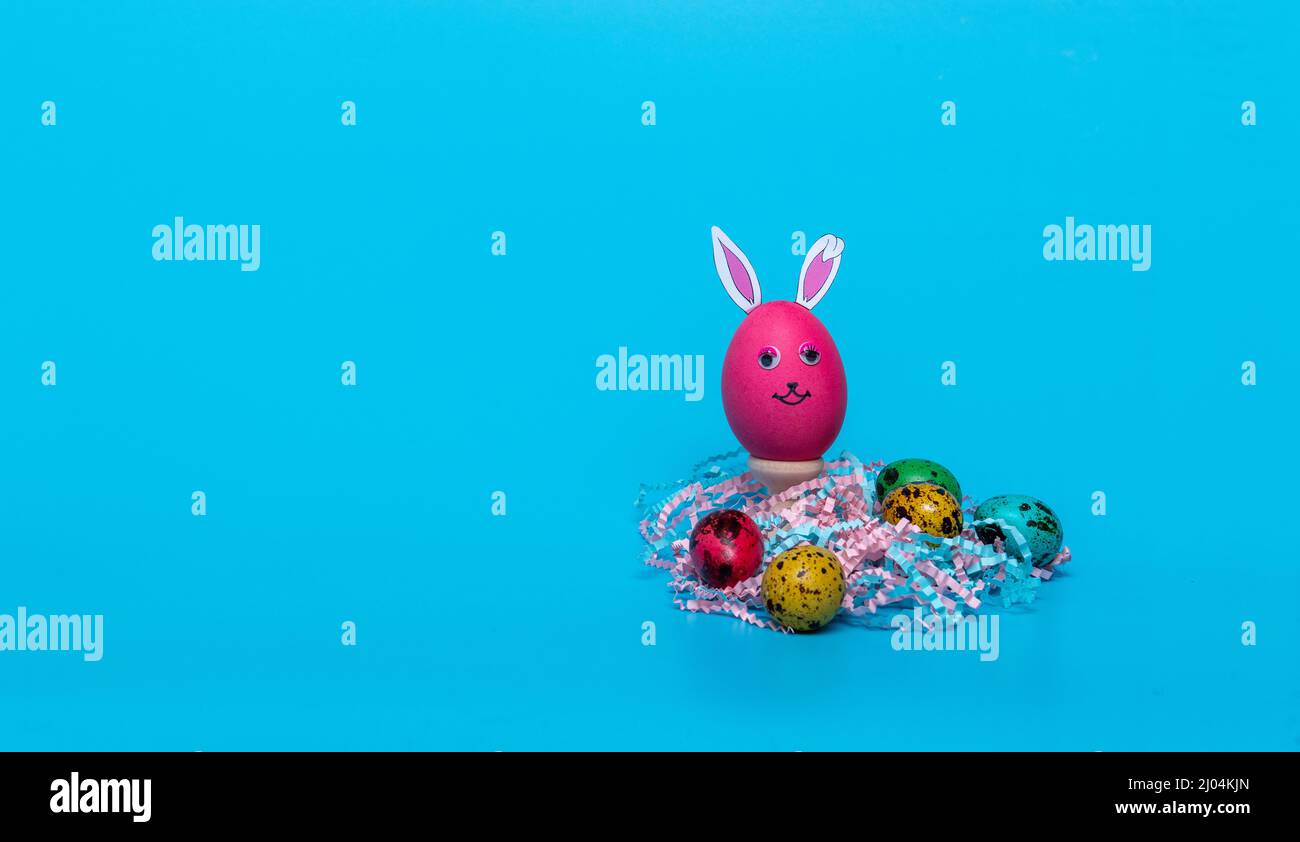 red Easter egg with ears and colored quail eggs Stock Photo
