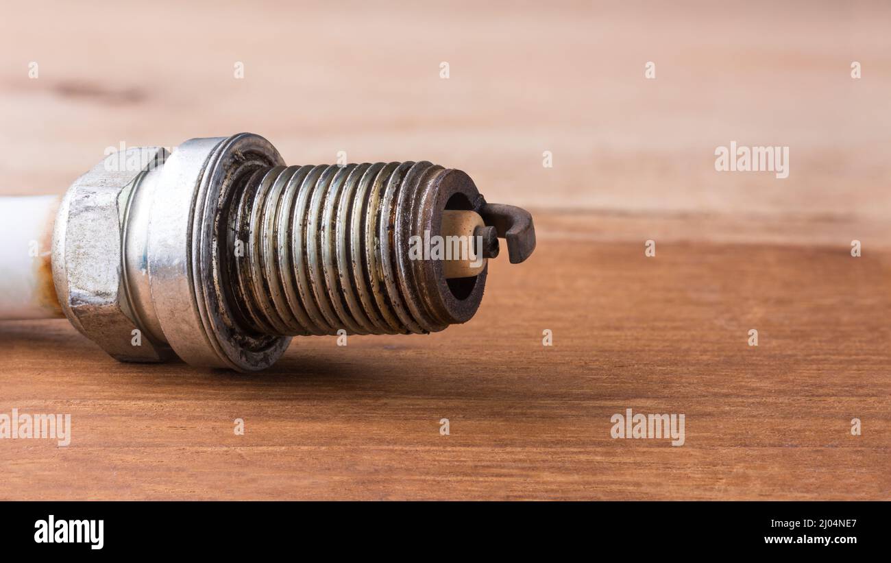used worn spark plug in shallow depth of field on a table top, closeup