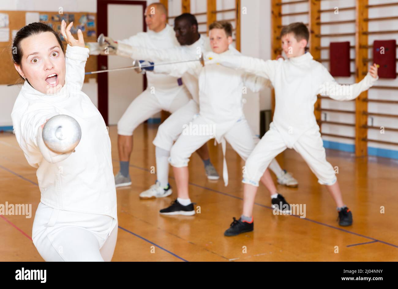 Young sporty woman training attack movements with rapier at fencing