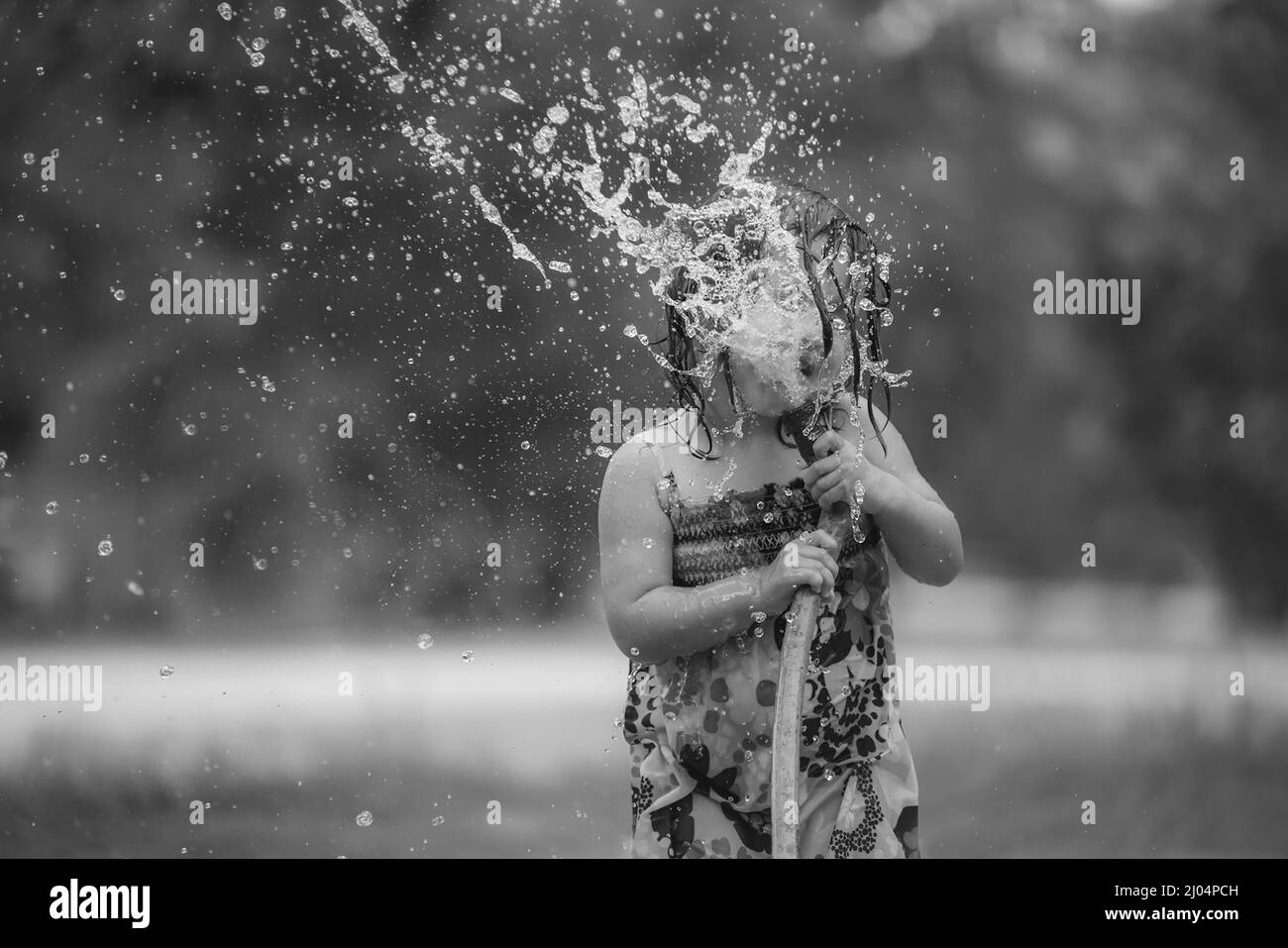 Child Playing In Water During Summer Time Stock Photo
