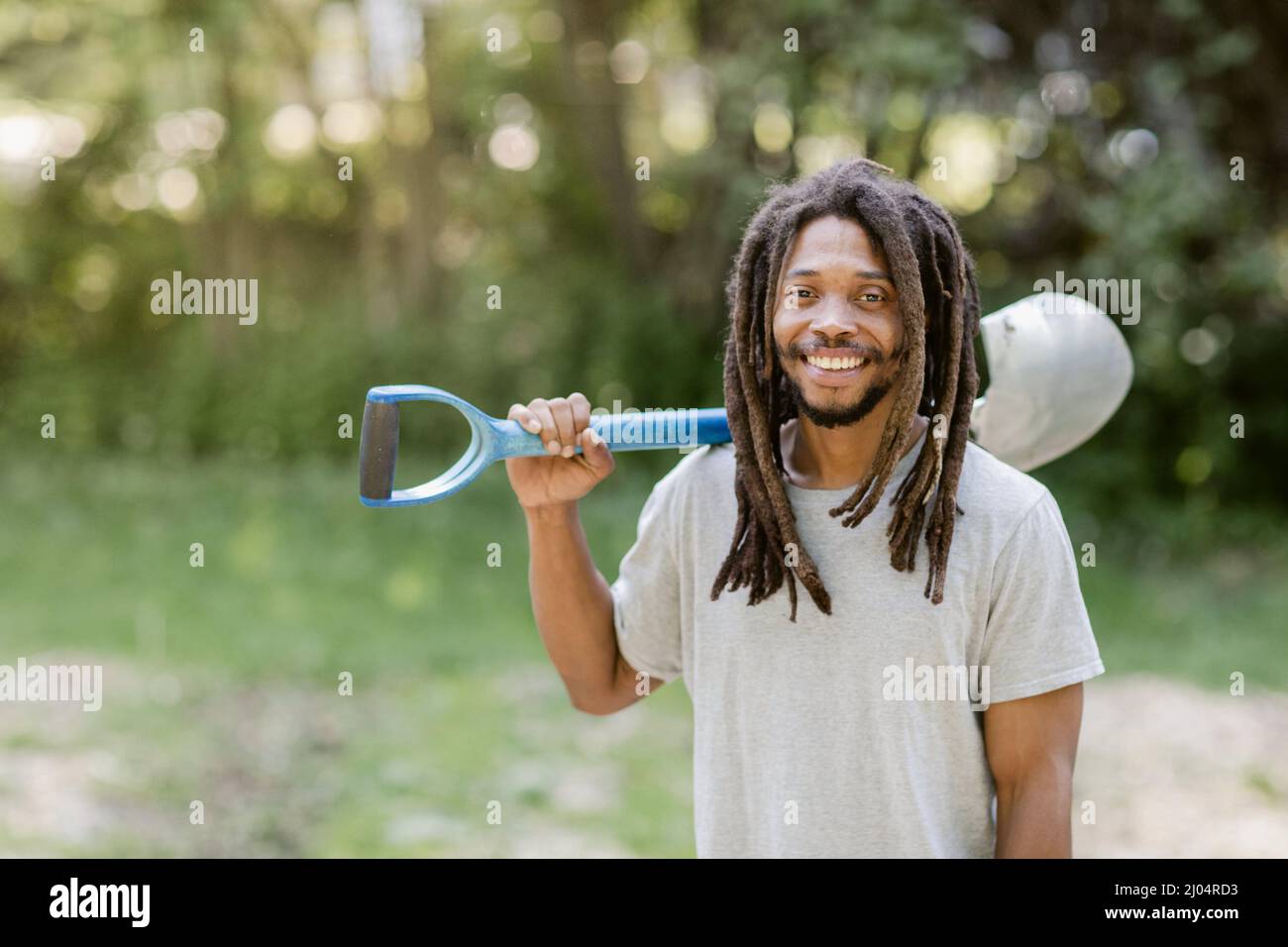 Smiling Black farmer holding a shovel over his shoulder on his farm ...