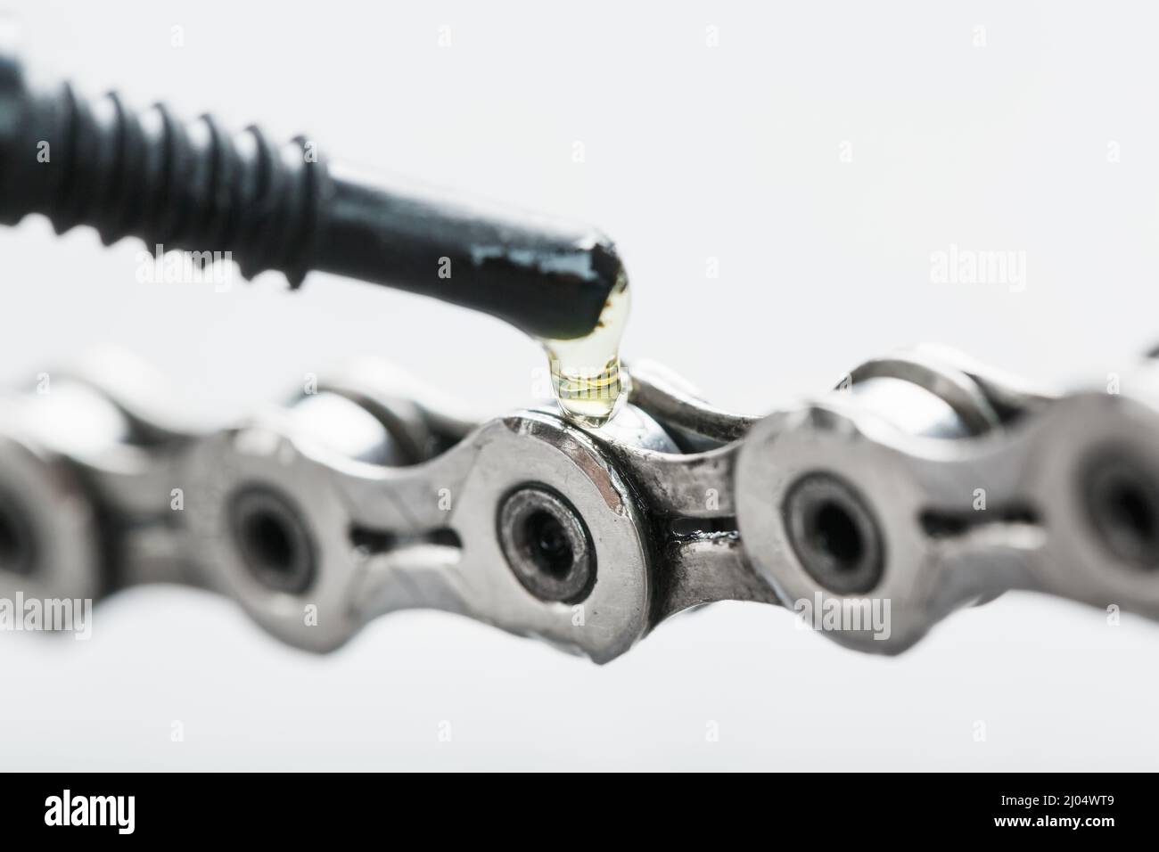 Lubricating a bicycle chain with a drop of oil closeup on an isolated