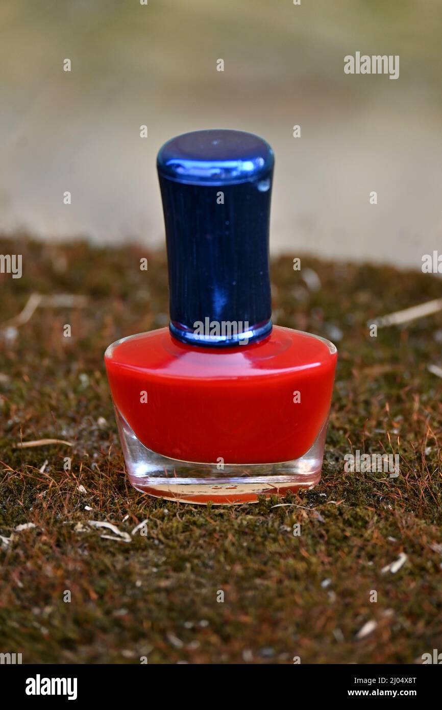 closeup the red color nail paint glass bottle blue cap over out of