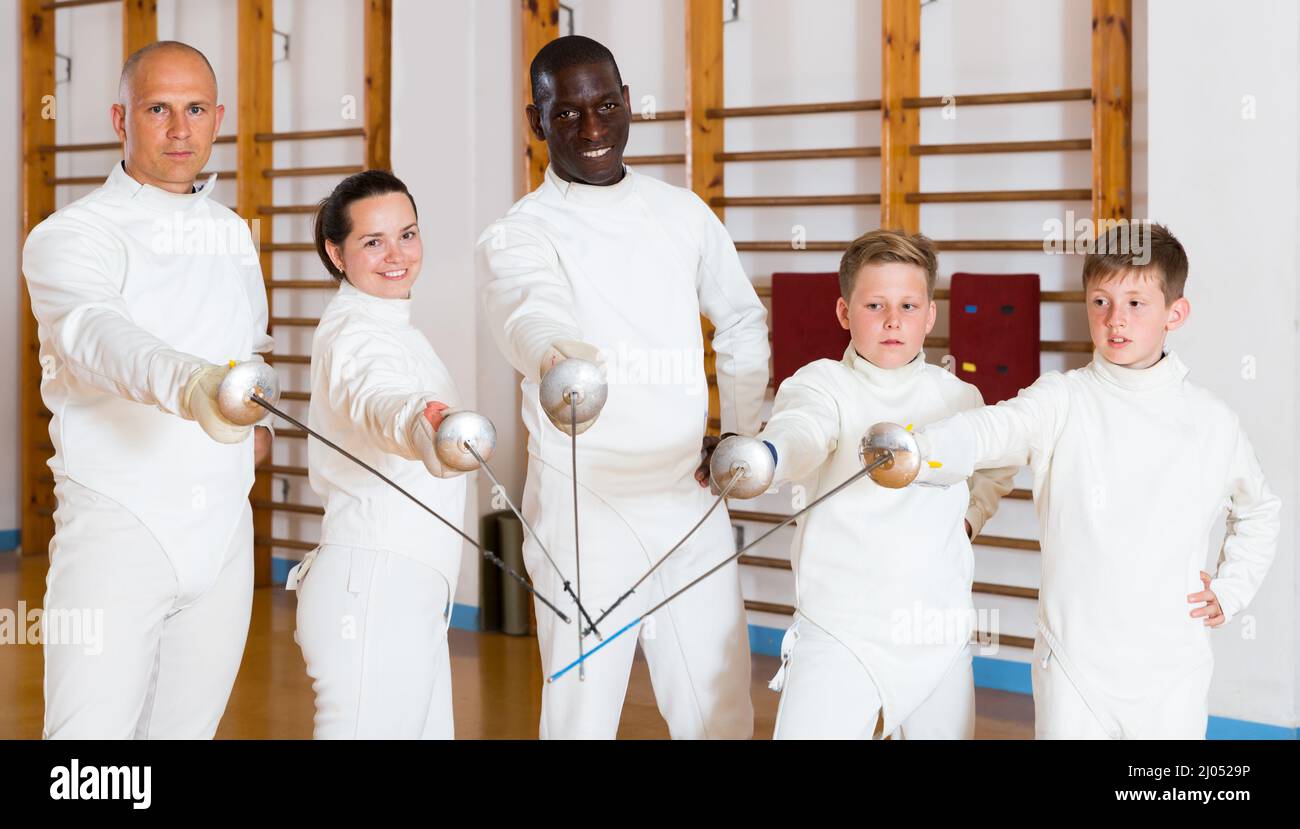 Portrait of cheerful mixed age group of athletes with foils at fencing