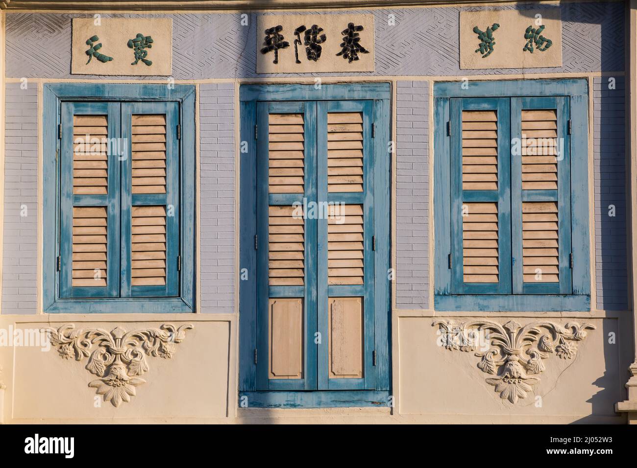 Wooden jalousie windows in baby blue and cream colour ways - early shophouse style. Singapore 2022 Stock Photo