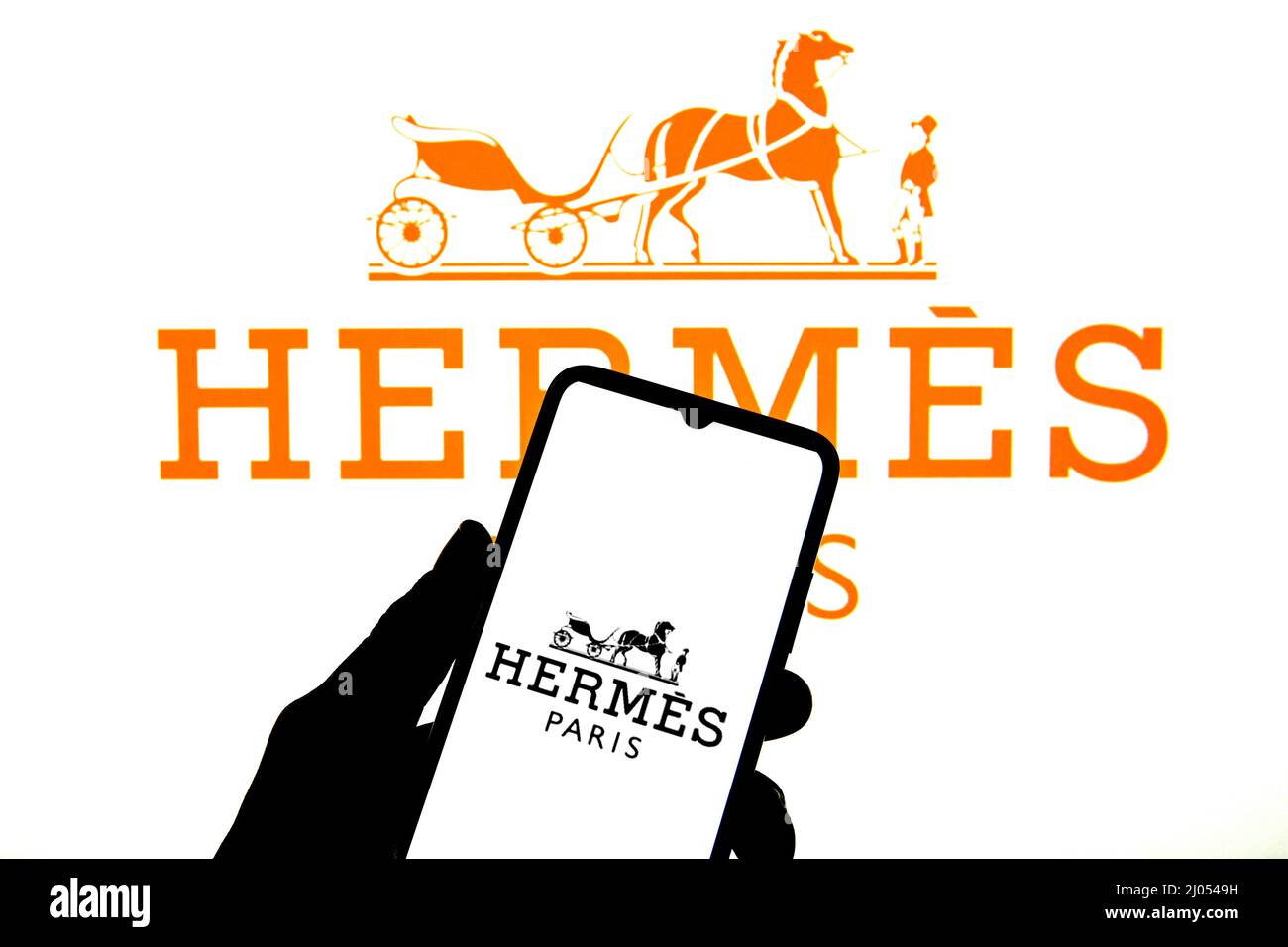 In this photo illustration a Hermes Paris logo seen displayed on a  smartphone with a Hermes Paris logo in the background Stock Photo - Alamy