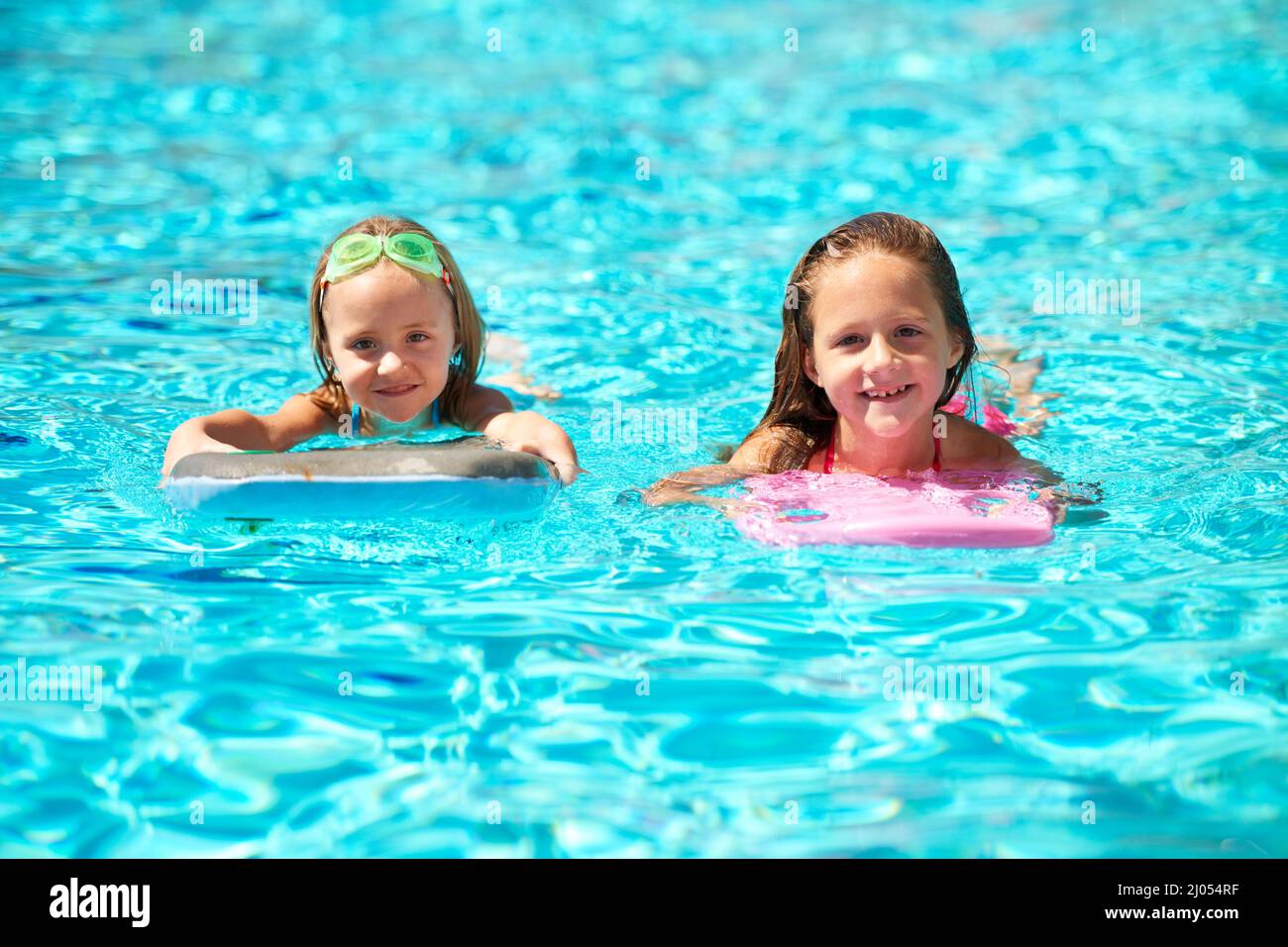 Summer rocks. Two little girls using pool inflatables while swimming Stock Photo Alamy