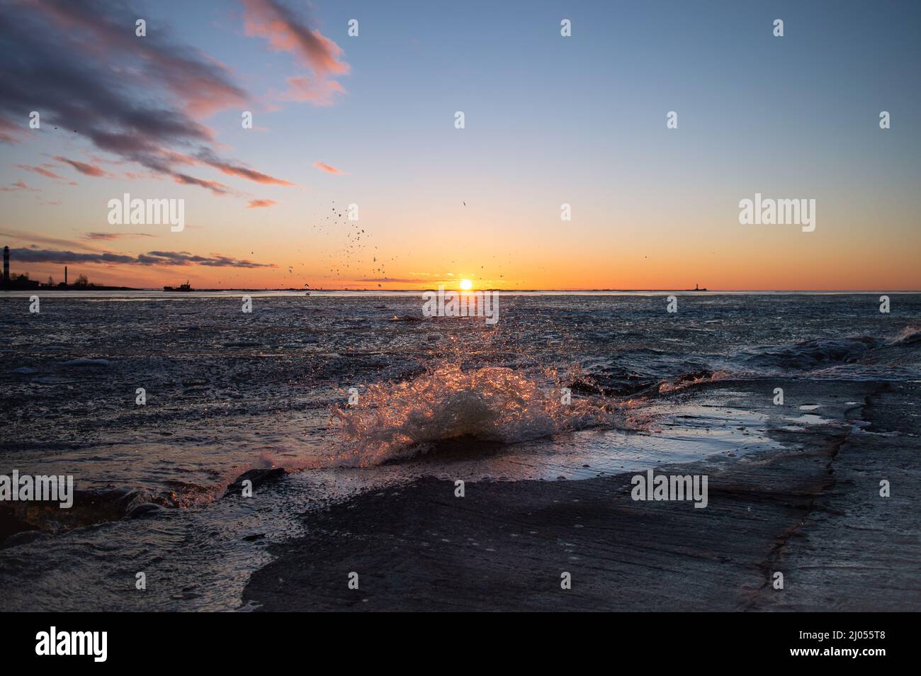 Sunset on the sea with breaking waves at pier Stock Photo - Alamy