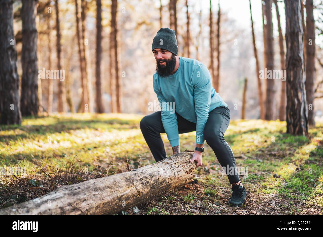 Strong sporty man is lifting tree stump Stock Photo - Alamy